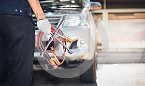 Auto mechanic holding vehicle maintenance equipment, battery charger and wheel wrench