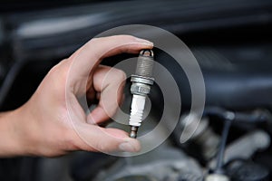 Auto mechanic holds an spark plug