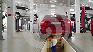 Auto mechanic inspects suspension, steering with hydraulic play detector in car repair shop. Technician analyzes vehicle