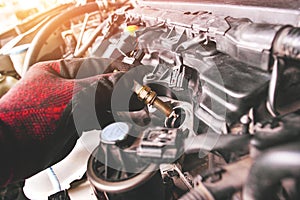 A auto mechanic is installing automobile iridium spark plugs into the ignition socket of the engine block