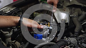 Auto mechanic installs LPG reducer vaporizer in car engine. Hands fix low pressure regulator for gas conversion
