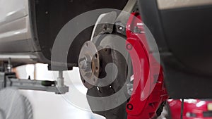 Auto mechanic installs new brake disc, caliper on vehicle. Car repair service procedure, maintenance workshop