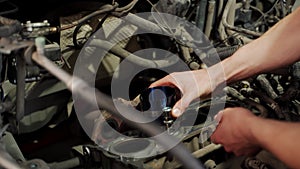 Auto mechanic installs piston using ring compressor tool in engine block for overhaul. Hands work meticulously aligning