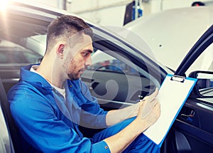 Auto mechanic man with clipboard at car workshop