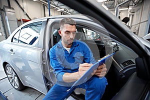 Auto mechanic man with clipboard at car workshop