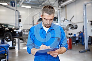 Auto mechanic man with clipboard at car workshop