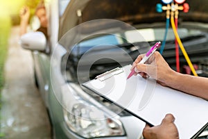 Auto mechanic perform vehicle checkup while service advisor take notes,Professional