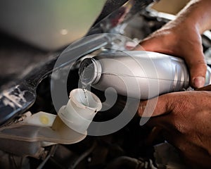 An auto mechanic pours brake fluid into the car