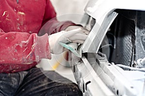 Auto mechanic prepairing the front bumper of a car