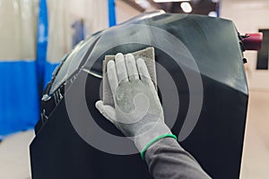 Auto mechanic preparing the car for paint job by applying polish with the power buffer machine
