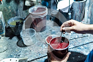 Auto mechanic preparing red car paint in a workshop.