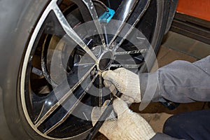 Auto mechanic in the process of replacing new tires. Repair of car brakes in the garage