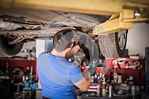 Auto mechanic repairer checking condition under car on vehicle lift