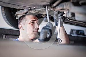 Auto mechanic repairer checking condition under car on vehicle lift
