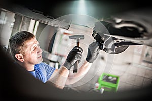 Auto mechanic repairer checking condition under car on vehicle lift