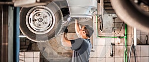 Auto mechanic repairer checking condition under car on vehicle lift