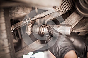 Auto mechanic repairer checking condition under car on vehicle lift