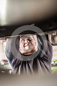 Auto mechanic repairer checking condition under car on vehicle lift