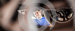 Auto mechanic repairer checking condition under car on vehicle lift