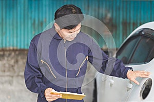 Auto mechanic repairman with a checklist, Technician checking modern car at garage