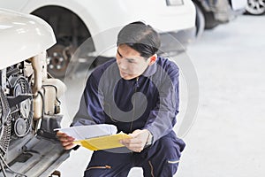 Auto mechanic repairman with a checklist, Technician checking modern car at garage