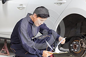 Auto mechanic repairman with a checklist, Technician checking modern car at garage, Car repair and maintenance concepts