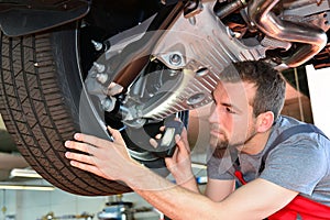 Auto mechanic repairs vehicle in a workshop