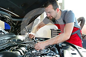 Auto mechanic repairs vehicle in a workshop