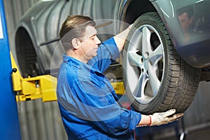 Auto mechanic screwing car wheel by wrench