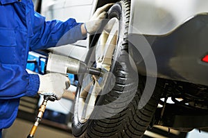 Auto mechanic screwing car wheel by wrench