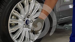 Auto mechanic secures tire on premium vehicle using torque wrench. Expert ensures wheel alignment, safety in high-end