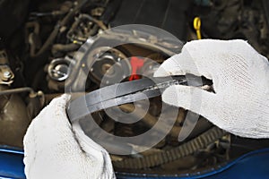 An auto mechanic shows a timing belt burst from the back side