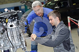 Auto mechanic shows trainee maintenance car engine