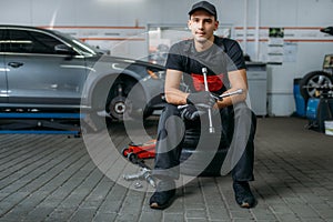 Auto mechanic sitting on wheels, tire service