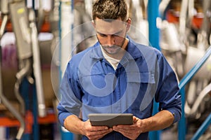 Auto mechanic or smith with tablet pc at workshop