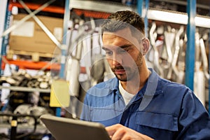 Auto mechanic or smith with tablet pc at workshop