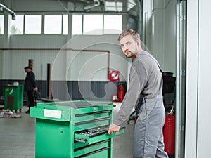 The auto mechanic takes the tool from the green tool box. Indoors .