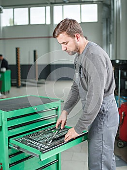 The auto mechanic takes the tool from the tool box. Indoors .