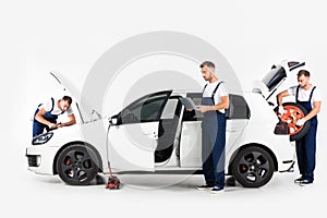 auto mechanic taking car tire using laptop and looking in open car hood photo