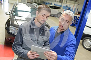 auto mechanic teacher and trainee performing tests at mechanic school