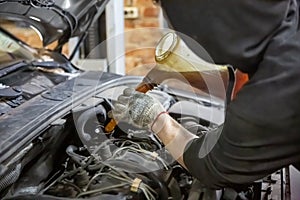 Auto mechanic technician replacing and pouring motor oil