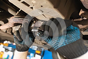 An auto mechanic tightens the oil drain plug in the car crankcase with a torque wrench