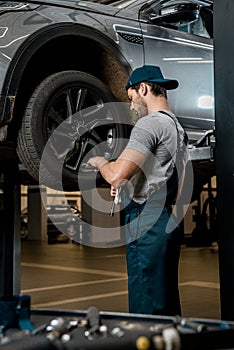 auto mechanic in uniform fixing car wheel