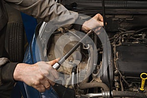 An auto mechanic unscrews the engine mount to replace the timing belt