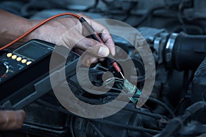 Auto mechanic using measuring equipment for checking car electrical.