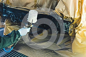 Auto mechanic wearing gloves painting a car in an auto repair shop car refinish photo