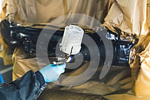 Auto mechanic wearing gloves painting a car in an auto repair shop car refinish photo