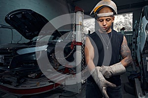 Auto-mechanic wearing welding gauntlets and protective helmet