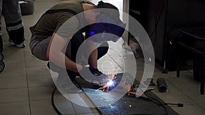 Auto mechanic welds exhaust flex pipe in workshop. Sparks fly as professional fixes car catalyst using welding gear