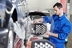 Auto mechanic at wheel alignment work with sensor photo